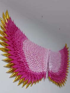 a pink and gold wall hanging on the side of a white wall, with spikes attached to it