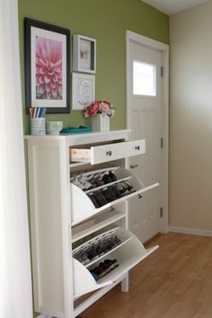 a white shoe rack in the corner of a room next to a door with pictures on it