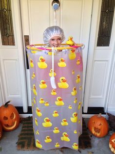 a woman in a costume with rubber ducks on her head and pumpkins around her