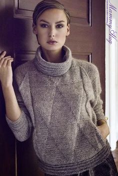 a woman leaning against a door wearing a sweater