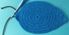 a crocheted blue piece of cloth next to a pair of scissors