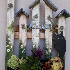 a wooden fence with birds and flowers on it next to succulents, cacti and other plants