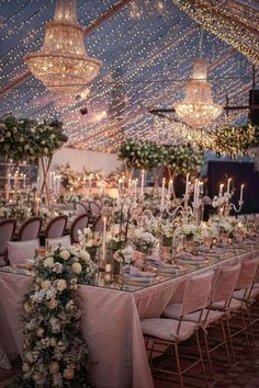 the tables are set up with white flowers and candles for an elegant dinner or reception