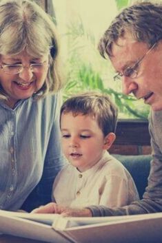 two adults and a child looking at a book