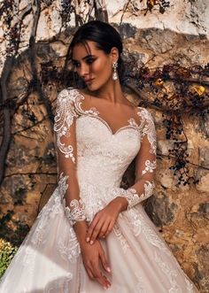 a woman in a wedding dress standing next to a stone wall