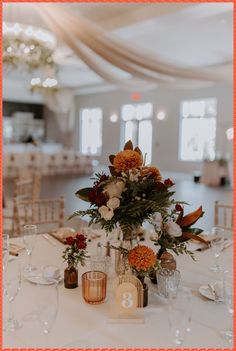 an elegant centerpiece with flowers and candles sits on a table in the middle of a banquet hall