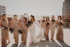 a group of women standing next to each other on top of a roof holding bouquets