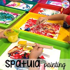 children are painting with colorful paints on trays