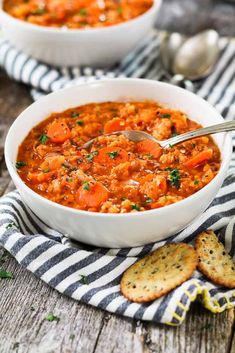 a white bowl filled with soup next to crackers