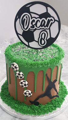 a soccer themed birthday cake with grass and icing on the top is decorated in black, white and green