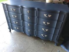 an old dresser is painted blue with gold leafy knobs and pulls on the drawers