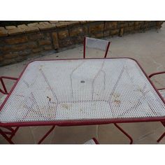 two chairs and a table are sitting on the concrete ground next to a brick wall