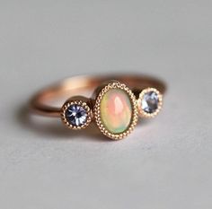 an opal and diamond ring is shown on a white surface with gold trimmings