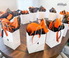 several white bags with orange and black bows on them are sitting on a round table