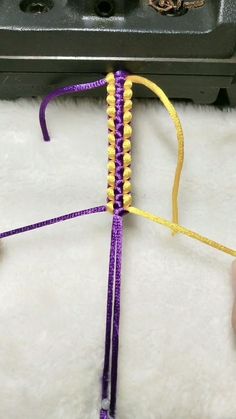 a purple and yellow string with beads attached to it sitting on a white fur covered floor