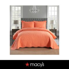 an orange bed in a bedroom next to a chandelier and two nightstands