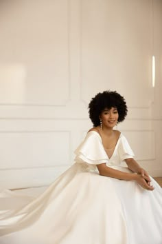 a woman sitting on the floor in a white dress