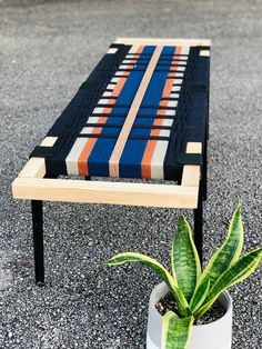 a small potted plant sitting on top of a wooden table next to a bench