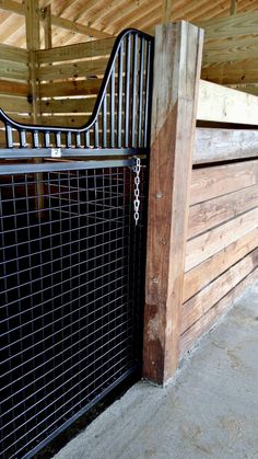 a horse is standing next to a fenced in area with wood and metal bars