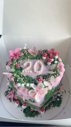 a heart shaped cake in a box with flowers and pearls on it's side