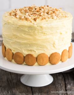 a cake with white frosting and nuts on top is sitting on a wooden table