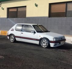 a white car parked in front of a building on the side of a road with no one around it