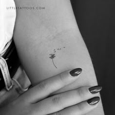 a woman's arm with a small flower tattoo on the left side of her arm