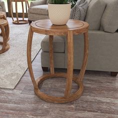 a wooden table with a potted plant on it in front of a couch and coffee table