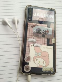 a cell phone sitting on top of a notepad next to ear buds and headphones