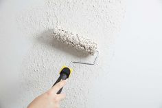 a person using a paint roller to paint a wall