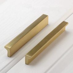 two brass door handles on white wood planks with one closed and the other open