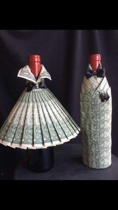 two wine bottles made out of money are sitting next to each other on a black surface