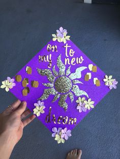 someone is holding up a purple graduation cap with flowers on it and the words, to my new dear