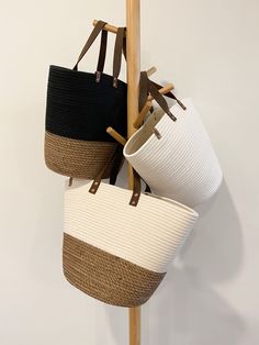 three baskets hanging from a wooden pole on top of each other in different colors and sizes