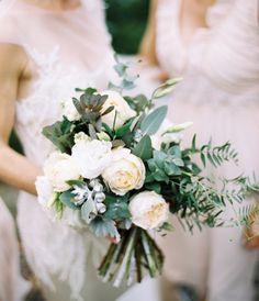 two women in white dresses holding bouquets of flowers