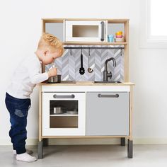 a little boy playing with a toy kitchen set