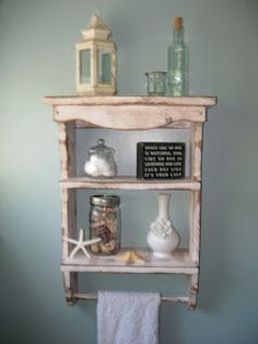 a shelf that has some jars on it and sand in front of it next to a towel rack