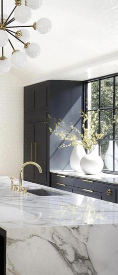 a kitchen with marble counter tops and black cabinetry in the background, along with a chandelier hanging from the ceiling