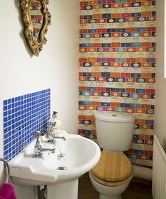 a bathroom with a toilet, sink and colorful wallpaper on the walls behind it