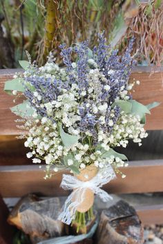 a bouquet of lavenders and baby's breath tied to a wooden bench outside