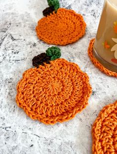 three crocheted coasters sitting on top of a table next to a cup