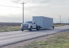 a truck driving down the road with a trailer attached to it