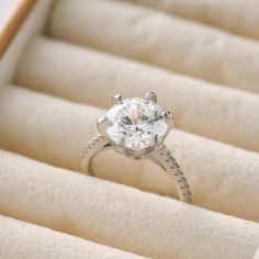 an engagement ring in a box with its lid open and the diamond set on top