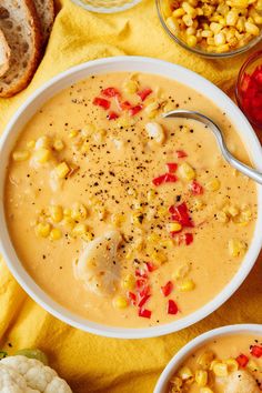 two bowls filled with soup next to some vegetables and bread on a yellow towel,