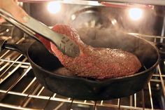 someone is cooking meat in an oven with tongs and a spatula on the pan