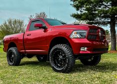 a red ram truck parked on top of a lush green field