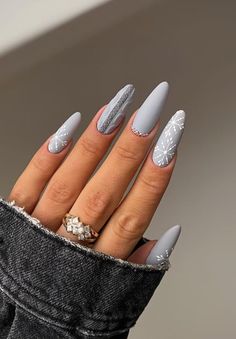 a woman's hand with grey and white nail polish on her nails, holding onto a pair of jeans