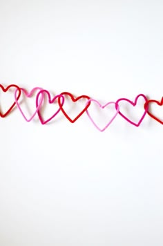 red and pink string with hearts hanging from it's ends on a white background