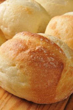 bread rolls sitting on top of a wooden cutting board