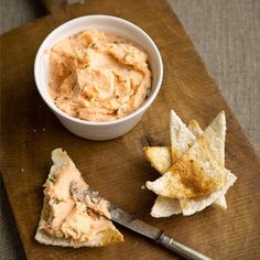 a wooden cutting board topped with chips and dip